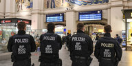 Vier Bundespolizisten in Uniform von hinten in der Halle des Bremer Hauptbahnhofs