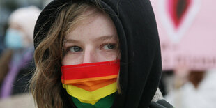 Eine Frau trägt eine Regenbogenmaske bei einem Protest