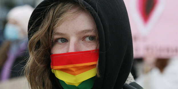 Eine Frau trägt eine Regenbogenmaske bei einem Protest