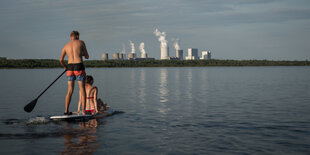 Badegäste beim Stand-Up-Paddling am Bärwalder See in der Nähe von Uhyst gegenüber dem Kohlekraftwerk Boxberg