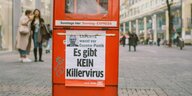An einer roten Zeitungsbox hängt ein Flyer, auf dem steht: "EXPERTE warnt vor Corona-Panik. Es gibt KEIN Killervirus."