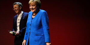 Angela Merkel und Alexander Osang verlassen lächelnd einen Raum