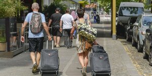 Zeit Reisende mit Rollkofern gehen über einen Bürgersteig