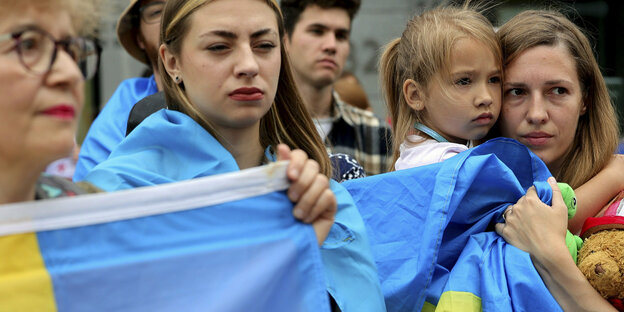 Frauen mit einer ukrainischen blau-gelben Fahne vor dem Europaparlament