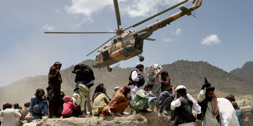 Eine kleine Gruppe von Menschen, über die ein Hubschrauber hinweg fliegt