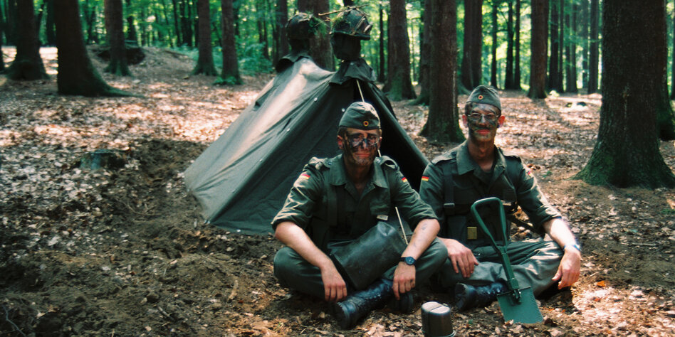 Zwei Bundeswehrsoldaten sitzen im Wald vor einem Zelt