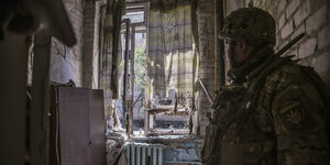 Ein Soldat schaut aus einem Fenster eines verwüsteten Hauses