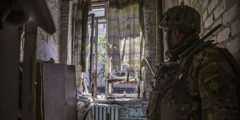 Ein Soldat schaut aus einem Fenster eines verwüsteten Hauses