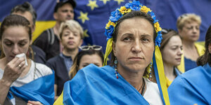 Eine Frau mit Ukraine Flaggen und tradtionellen Kopfschmuck demonstriert