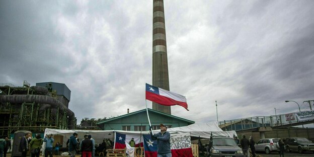 Ein Mann weht die Flagge von Chile vor einer Kupfer-Raffinerie