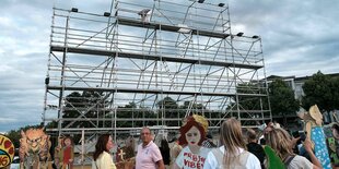 Leeres Gerüst auf dem Kassler Friedrichsplatz mit Menschen davor