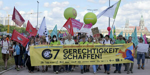 Demonstrant*innen mit Banner: "G7 - Gerechtigkeit schaffen"