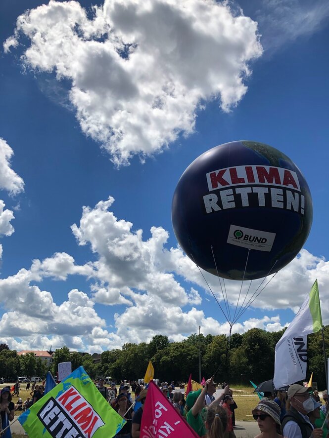 Demo, blauer Himmel, einzelne Wolken, riesiger Luftballong mit der Aufschrift "Klima retten"