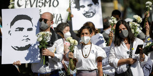 Menschen demonstrieren mit Blumen und Plakaten