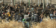 Migranten stehen eingekeilt von Beamten der Guardia Civil an Melillas Grenzzaun, den sie ein Stück weggerissen haben.