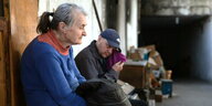 Eine ältere Frau und ein Mann sitzen erschöpft auf einer Bank