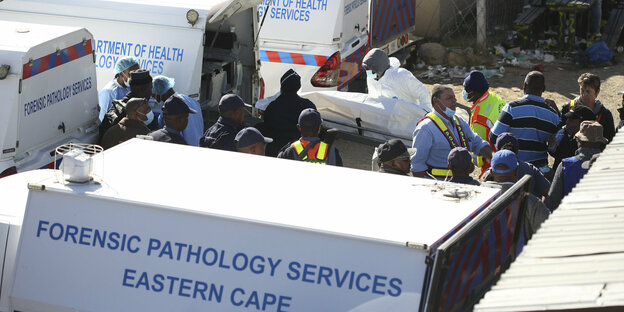 Verladung einer verhüllten Leiche in einen Transporter der südafrikanischen Behörden.