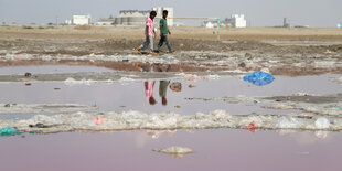 Landschaft mit gefärbten Wasserlachen, am Horizont Fabriken