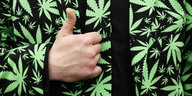 Teilnehmer einer Demo trägt Anzug mit einem Cannabis Muster und zeigt Daumen hoch
