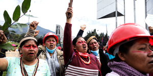 Eine Gruppe von indigenen Frauen mit Helmen streckt die Fäuste in die Höhe