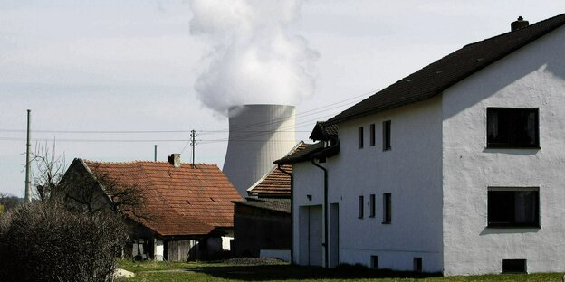Der Kühlturm des Reaktors Isar 2 schaut hinter Einfamilienhäusern hervor