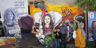 Palästinenser:innen vor einer Gedenkwand für Shireen Abu Akleh