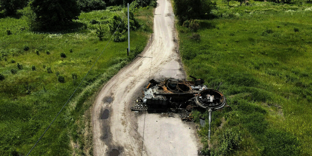 Ein zerschossener Panzer liegt auf einer menschenleeren Straße