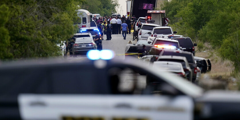 LKW-Auflieger mit offener Hecktür, umgeben von Polizisten auf einer abgesperrten Straße