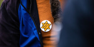 Ein Teilnehmer einer Kundgebung trägt einen symbolischen Judenstern mit der Aufschrift "„Maskenbefreit“" auf seiner Brust.