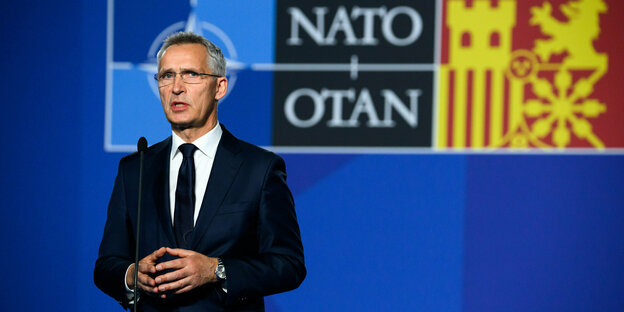 Jens Stoltenberg vor blauem Hintergrund mit Hinweisen auf die NATO