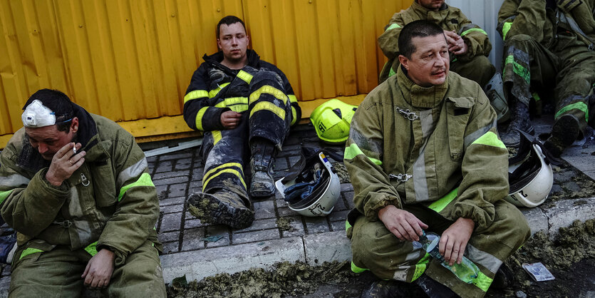 erschöpfte Rettungskräfte sietzen auf dem Boden