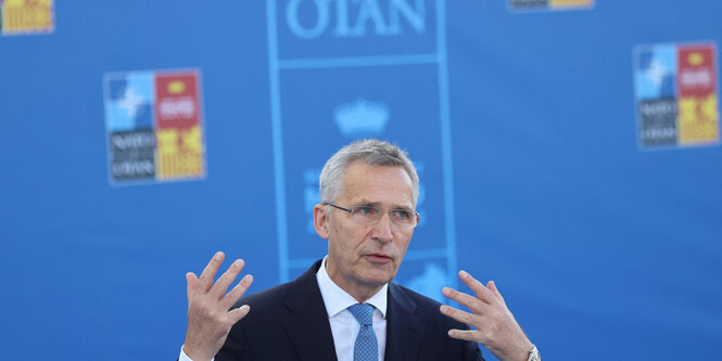 Stoltenberg gestikuliert vor blauem Hintergrund