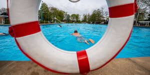 Blick durch einen Rettungsring auf einen Schwimmer im Freibad