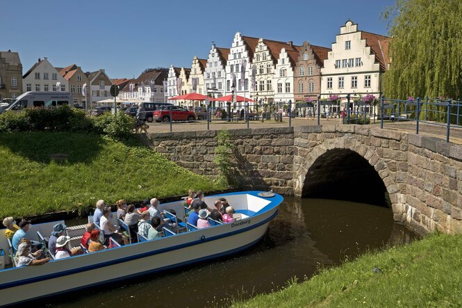 Ausflugsboot in einer Gracht vor der Kulisse von Friedrichstadt