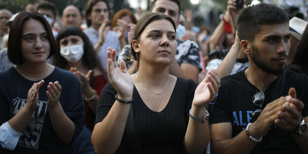 Traurige junge schwarz gekleidete Menschen klatschen bei einer Demonstration in die Hände