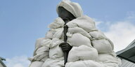 Eine Statue mit Gewehr ist komplett mit Sandsäcken eingehüllt