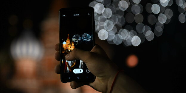 Auf dem Display eines Smartphones erscheint das Foto eines Feuerwerks