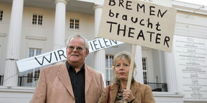 Ein Mann und eine Frau halten ein Plakat hoch, auf dem steht: "Bremen braucht Theater"