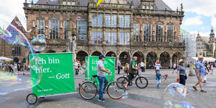 Vor dem Bremer Rathaus ziehen Radfahrer große Banner mit Slogans hinter sich her