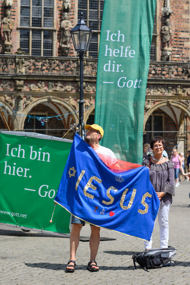 Mann steht mit Fahne, auf der Jesus steht, vor dem Bremer Rathaus