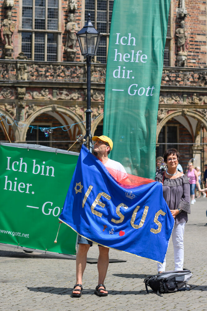 Mann steht mit Fahne, auf der Jesus steht, vor dem Bremer Rathaus