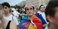 Eine Gruppe von Menschen, einer trägt eine Regenbogenfahne als Gewand