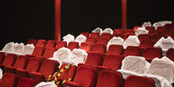 leere Kinostuhlreihen, einige Sitze sind mit einem weißen Bezug markiert, teils ist Absperrband über den Sitzen