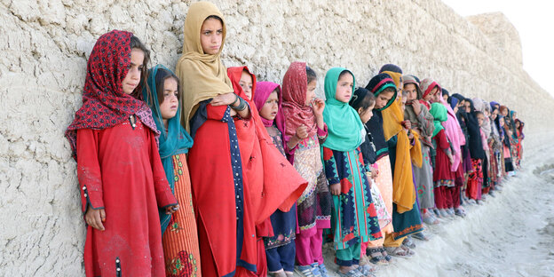 Kinder stehen mit Kopftüchern vor einer Mauer