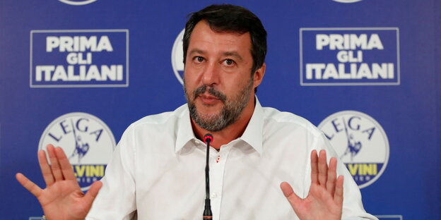 Salvini sitzt vor einer Pressewand
