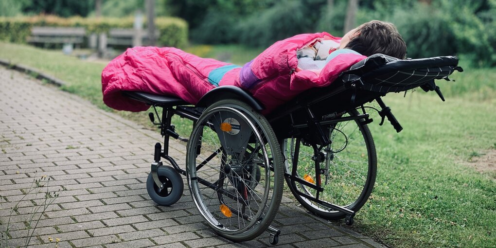 Ein Kind in einem Schlafsack im Liegerollstuhl