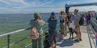 Menschen stehen an einem Schiffsanleger in Kiel.