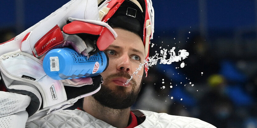 Eishockeyspieler Iwan Fedotow trinkt aus einer Flasche.