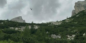 Ein Rettungshubschrauber fliegt über bergige Landschaft.