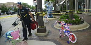 Ein Polizist läuft vorbei an Kinderfahrrädern und Absperrfahnen
